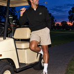 The Back Nine Quarter-Zip with SSC monogram, leaning on a golf cart | Sunday Swing Club