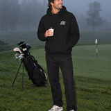 Sunday Classic Hoodie in Black with coffee at the misty putting green | Sunday Swing Club